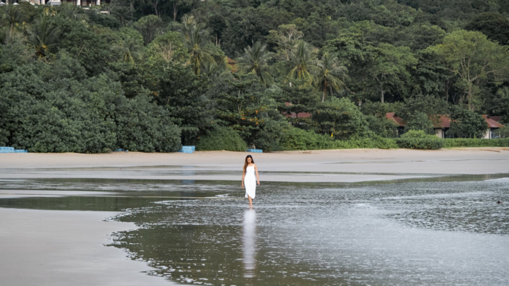 A beautiful woman in a white dress wades in the shallow surf at Bakantiang Beach