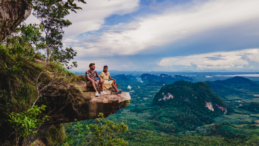 A couple overlooks a dramatic view of Krabi Thailand from the outcropping rock at Dragon Crest Mountain