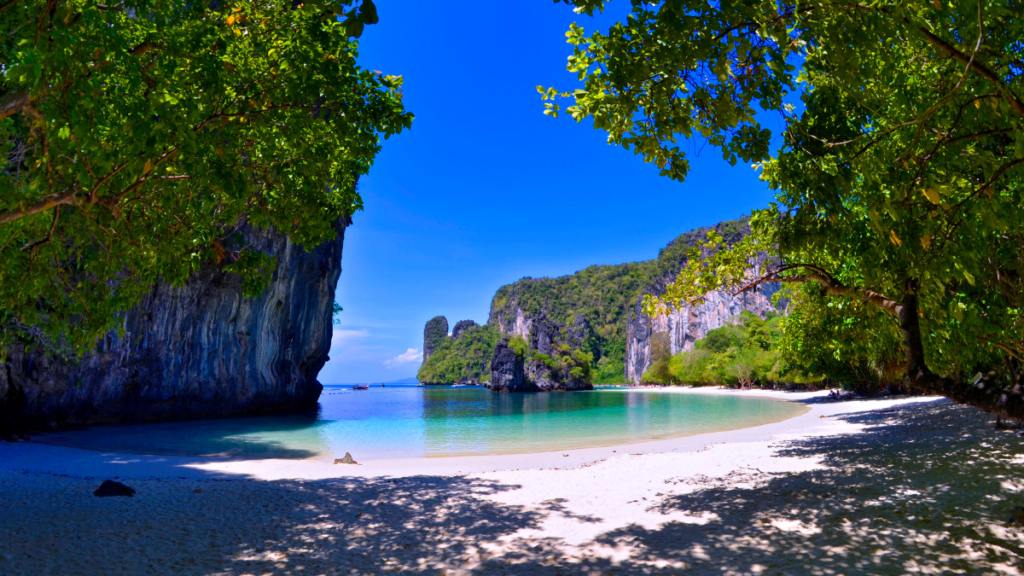 Light and shade interplay on the beach framed by limestone cliffs at Hong Island, Thailand