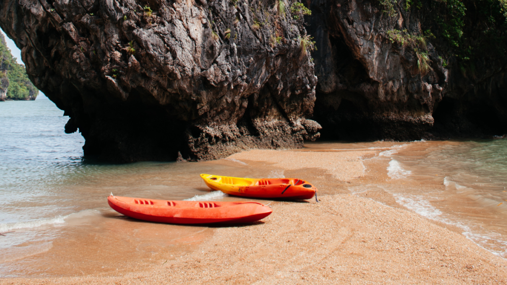 Kayaks on a stretch of golden sand among karst formations on Koh Talabeng